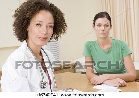 Stock Image - Woman in doctor's office frowning. Fotosearch