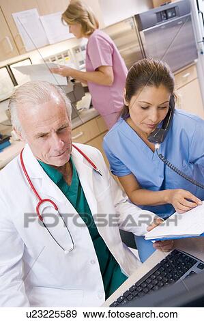 Stock Photo - A Doctor And Nurse At The Reception Area Of A Hospital. Fotosearch