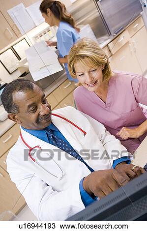 Stock Image - A Doctor And Nurse Discussing Something At The Reception Area Of A Hospital. Fotosearch