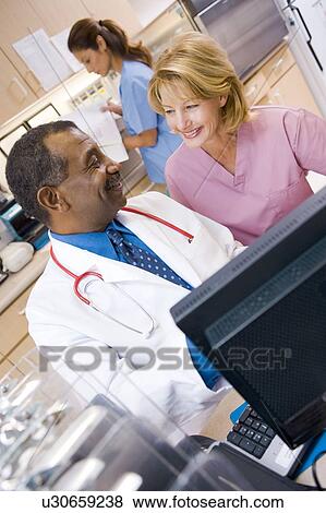 A Doctor And Nurse Discussing Something At The Reception Area Of A Hospital View Large Photo Image Stock Photo - A Doctor And Nurse Discussing Something At The Reception Area Of A Hospital. Fotosearch