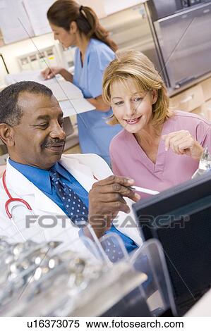 Stock Photography - A Doctor And Nurse Discussing Something At The Reception Area Of A Hospital. Fotosearch