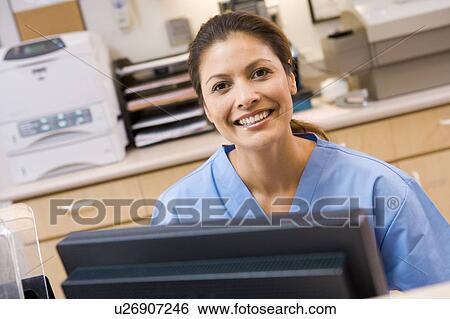 A Nurse Sitting At A Computer At The Reception Area Of A Hospital View Large Photo Image Stock Photograph - A Nurse Sitting At A Computer At The Reception Area Of A Hospital. Fotosearch