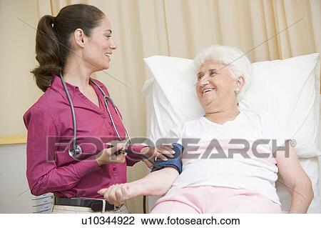 Doctor checking woman's blood pressure in exam room smiling View Large Photo Image Stock Image - Doctor checking woman's blood pressure in exam room smiling. Fotosearch
