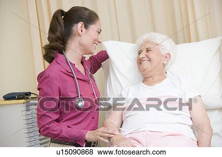 Doctor giving checkup to woman in exam room smiling View Large Photo Image Stock Photo - Doctor giving checkup to woman in exam room smiling. Fotosearch