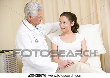 Doctor giving woman checkup in exam room View Large Photo Image Stock Photograph - Doctor giving woman checkup in exam room. Fotosearch