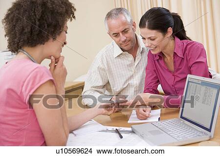 Picture - Doctor with laptop and couple in doctor's office smiling. Fotosearch