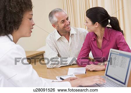 Doctor with laptop and couple in doctor's office smiling View Large Photo Image Stock Photograph - Doctor with laptop and couple in doctor's office smiling. Fotosearch