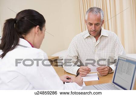 Stock Photograph - Doctor with laptop and man in doctor's office. Fotosearch