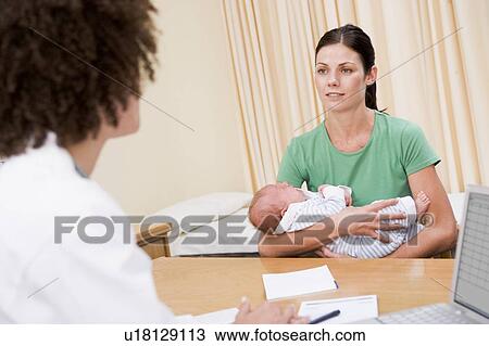 Doctor with laptop and woman in doctor's office holding baby View Large Photo Image Stock Image - Doctor with laptop and woman in doctor's office holding baby. Fotosearch