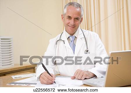 Doctor with laptop writing in doctor's office View Large Photo Image Stock Image - Doctor with laptop writing in doctor's office. Fotosearch