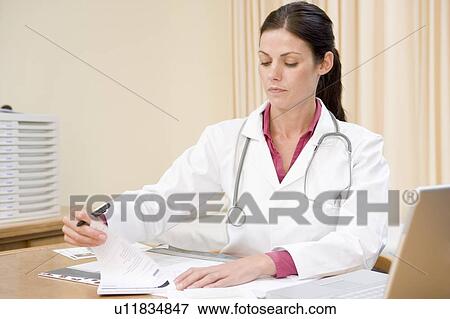 Doctor with laptop writing in doctor's office smiling View Large Photo Image Stock Photo - Doctor with laptop writing in doctor's office smiling. Fotosearch