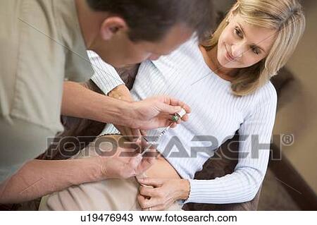 Stock Image - Man helping woman inject drugs to prepare for IVF treatment (selective focus). Fotosearch