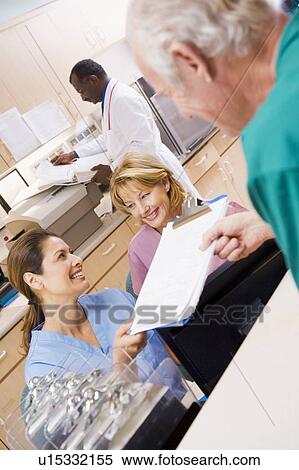 Stock Photography - Nurses Being Handed A Clipboard At The Reception Area In A Hospital. Fotosearch