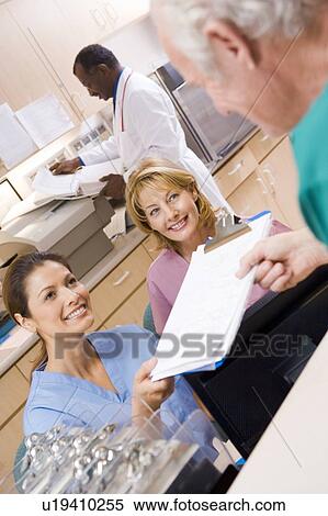 Stock Photography - Nurses Being Handed A Clipboard At The Reception Area In A Hospital. Fotosearch