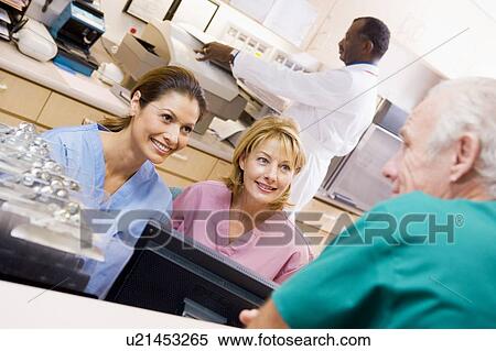 Stock Photography - Nurses Talking At The Reception Area In A Hospital. Fotosearch