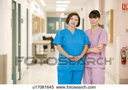 Stock Image - Two Female Nurses Standing In A Hospital Corridor. Fotosearch