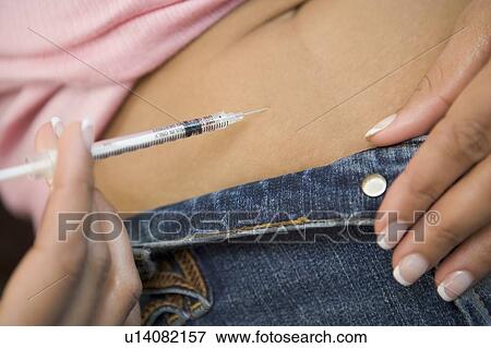 Stock Photo - Woman injecting drugs to prepare for IVF treatment. Fotosearch