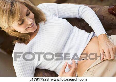 Stock Photo - Woman injecting drugs to prepare for IVF treatment. Fotosearch