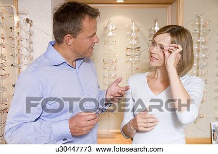 Stock Image - Couple trying on eyeglasses at optometrists. Fotosearch