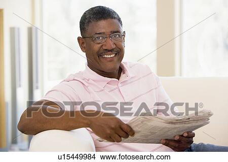 Picture - Man relaxing with a newspaper smiling. Fotosearch
