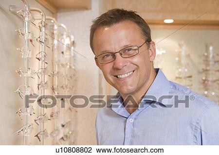 Man trying on eyeglasses at optometrists smiling View Large Photo Image Stock Image - Man trying on eyeglasses at optometrists smiling. Fotosearch