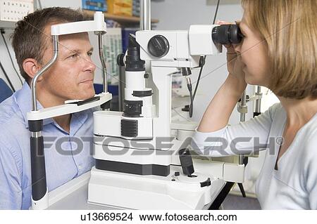 Picture - Optometrist in exam room with man in chair. Fotosearch