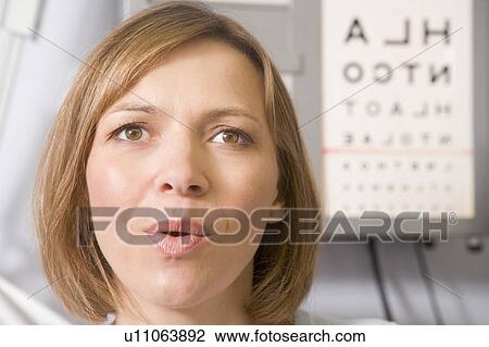 Stock Image - Woman in optometrist's exam room taking deep breath. Fotosearch