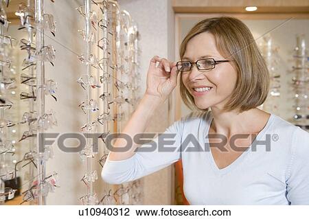 Woman trying on eyeglasses at optometrists smiling View Large Photo Image Stock Image - Woman trying on eyeglasses at optometrists smiling. Fotosearch