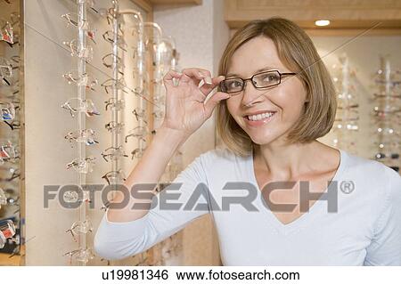 Woman trying on eyeglasses at optometrists smiling View Large Photo Image Stock Photograph - Woman trying on eyeglasses at optometrists smiling. Fotosearch