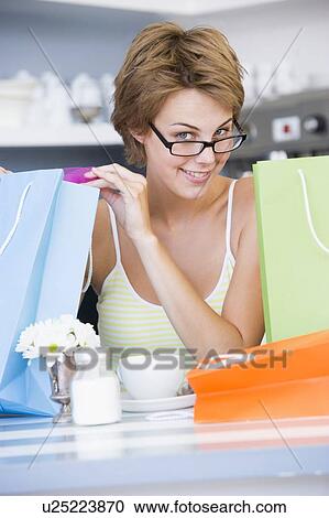 Young woman sitting at a table taking a break from shopping and drinking tea View Large Photo Image Stock Image - Young woman sitting at a table taking a break from shopping and drinking tea. Fotosearch