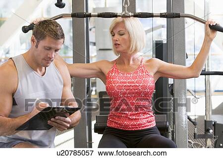 Stock Photo - Personal Trainer Watching Woman Weight Train. Fotosearch