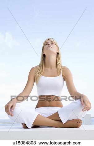 Stock Image - Woman sitting and meditating outdoors. Fotosearch