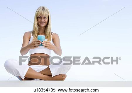 Stock Photography - Woman sitting and meditating outdoors while holding a candle. Fotosearch