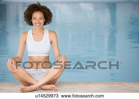 Stock Image - Woman sitting poolside smiling. Fotosearch