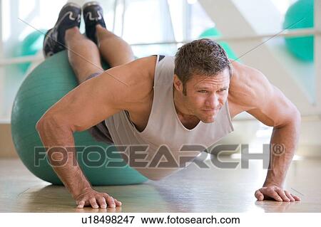 Stock Photo - Man Balancing On Swiss Ball At Gym. Fotosearch