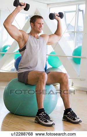 Man Using Hand Weights On Swiss Ball At Gym View Large Photo Image Stock Photo - Man Using Hand Weights On Swiss Ball At Gym. Fotosearch