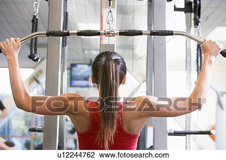 Stock Image - Woman Weight Training At Gym. Fotosearch