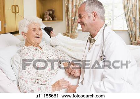 Stock Image - Doctor Laughing With Senior Woman In Hospital. Fotosearch