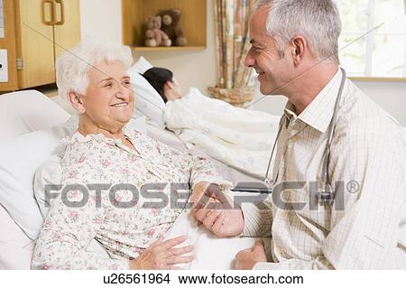 Doctor Sitting With Senior Woman In Hospital View Large Photo Image Picture - Doctor Sitting With Senior Woman In Hospital. Fotosearch