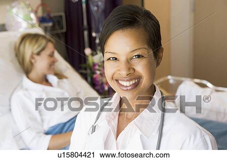 Stock Image - Doctor Standing In Her Patients Room. Fotosearch