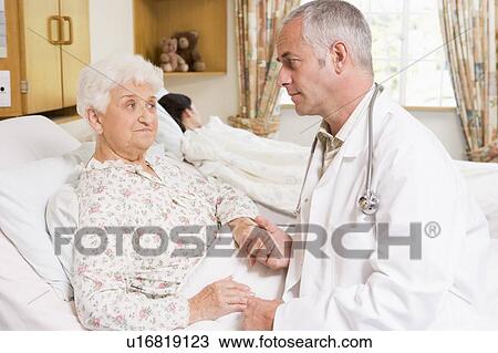 Stock Image - Doctor Talking With Senior Woman Patient In Hospital. Fotosearch