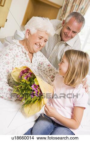 Picture - Granddaughter Giving Flowers To Her Grandmother In Hospital. Fotosearch
