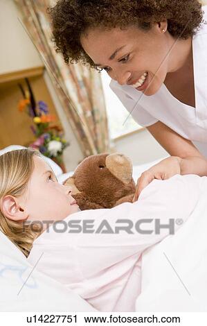 Stock Image - Nurse Checking Up On Young Girl In Hospital. Fotosearch