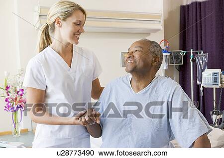 Stock Image - Nurse Helping Patient Sit Up In Bed. Fotosearch