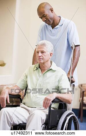 Stock Image - Nurse Pushing Man In Wheelchair. Fotosearch