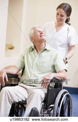 Stock Image - Nurse Pushing Man In Wheelchair. Fotosearch