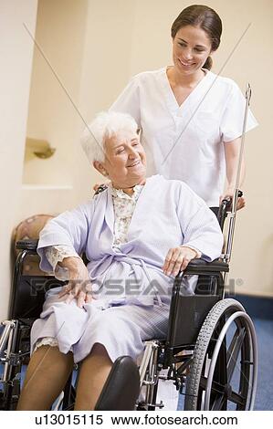 Stock Photography - Nurse Pushing Woman In Wheelchair. Fotosearch