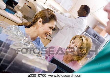 Stock Image - Nurses Talking At The Reception Area In A Hospital. Fotosearch