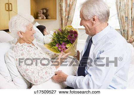 Stock Photo - Senior Man Giving Flowers To His Wife In Hospital. Fotosearch