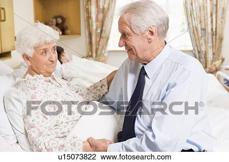 Stock Image - Senior Man Sitting With His Wife In Hospital. Fotosearch